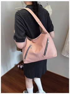 Pink lychee texture tote bag with silver zippers shown on shoulder for size reference