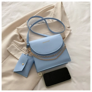 Détail d'un sac bandoulière bleu clair avec chaîne dorée et mini pochette assortie