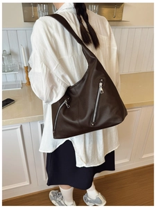 Close-up of dark brown lychee texture leather bag with decorative silver zippers