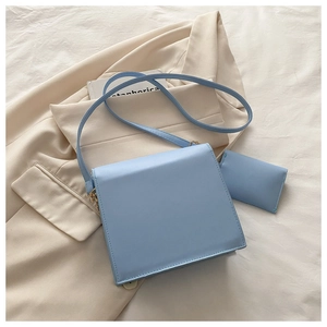 Détail du sac bandoulière carré bleu clair avec mini pochette sur blazer beige