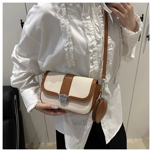 Detail of crossbody saddle bag with woven texture, brown leather trim, and coin purse