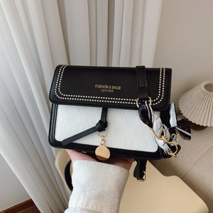 Detail of black and white contrast leather crossbody bag with gold logo and silk scarf deco