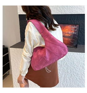 Detail shot of a magenta crescent bag featuring stitched suede texture and a wide shoulder strap