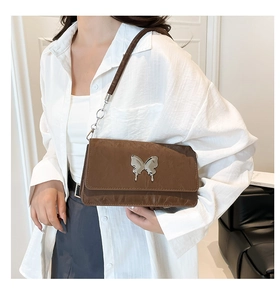 Close-up of a brown wrinkled faux leather shoulder bag with a silver butterfly metal buckle