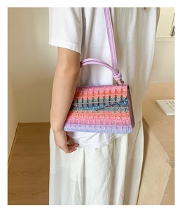 Detail of colorful rainbow woven crossbody bag with purple leather handle and vibrant stripes
