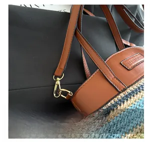 Close-up of golden metal hooks and leather straps on a woven color-block shoulder bag