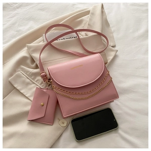 Ensemble sac à épaule rose avec chaîne dorée et petit porte-monnaie sur tissu beige