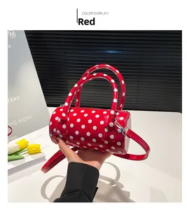 Dettaglio ravvicinato di una borsa a cilindro rossa a pois con doppi manici e tracolla