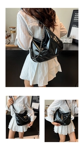 Detail view of large black patent leather crescent bag with chain strap and plush charm