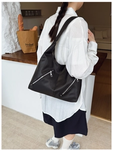Detail of black pebbled leather tote bag with dual zippers and comfortable wide strap