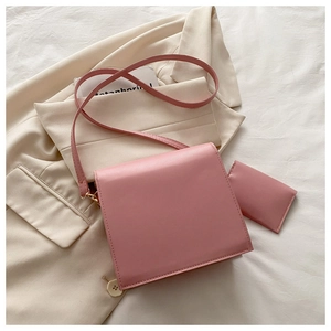 Vue détaillée du sac bandoulière rose pâle avec porte-carte sur blazer beige et drap blanc