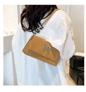 Detail of mustard yellow pleated patent leather bag with silver butterfly metal buckle