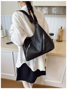 Detail of black large capacity hobo bag featuring silver zippers and pebbled leather texture