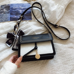 Detail of contrast square bag with lychee grain leather, silk scarf, and gold lettering