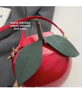 Détail macro du sac en forme de pomme montrant le cuir verni brillant et les surpiqûres