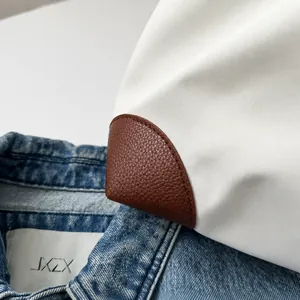 Primer plano de la esquina de cuero marrón y la tela blanca del bolso de viaje