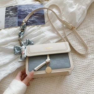 Detail of color-block flap bag with lychee texture leather and silk scarf accessory