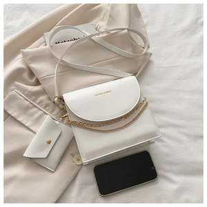 Détail d'un sac à bandoulière blanc minimaliste en similicuir avec chaîne dorée et pochette