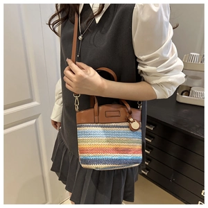 Detail view of woven bohemian crossbody bucket bag with multi-color patterns and leather strap