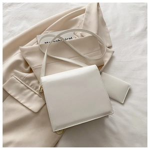 Détail du sac à bandoulière blanc minimaliste avec finitions dorées sur un blazer chic