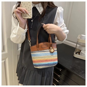 Detailed close-up of colorful striped woven texture and brown leather strap on bucket bag