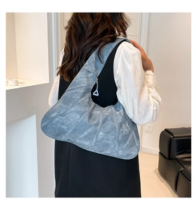 Close-up of a grey-blue crescent tote bag with vertical shell-like stitching texture