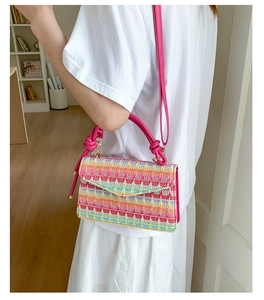 Detail of colorful geometric wave woven pattern bag with pink knotted handle and strap