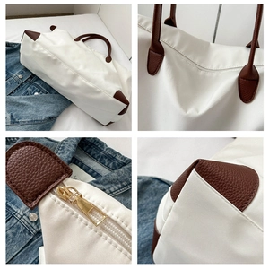 Detalles de bolso de viaje blanco con asas de cuero marrón y cremallera dorada de alta calidad.
