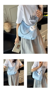 Close-up of light blue patent leather tote bag with silver chain and white plush charm
