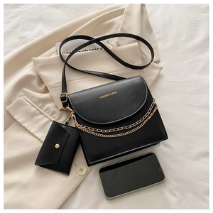 Détail du sac bandoulière en cuir noir avec chaîne dorée et petit porte-monnaie