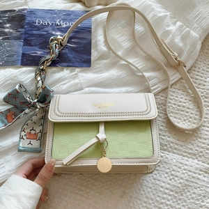 Detail of a white and green crossbody bag with lychee texture and silk scarf decoration