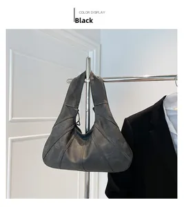 Detail of black tote bag with geometric stitching hanging next to a suit