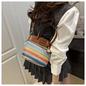 Detail of rainbow striped woven bucket bag with leather handles and Fashion label