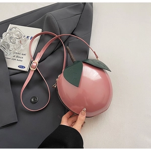 Gros plan du sac bandoulière rose en forme de pêche avec feuille verte et fini brillant