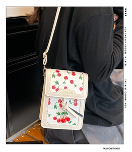 Macro detail of a white phone bag with cherry print and decorative cherry pendant