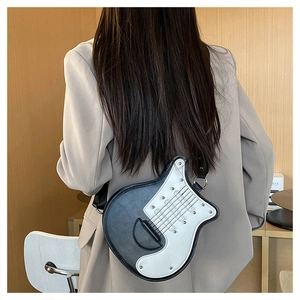 Détail du sac bandoulière en forme de guitare en cuir noir et blanc avec clous argentés