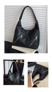 Detail view of black pebble leather Hobo bag featuring silver zippers and twin front pockets