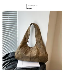 Close-up of brown vintage hobo bag with stitched details on leather and wide strap