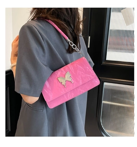 Detail of pink pleated shoulder bag with silver butterfly buckle on a grey suit