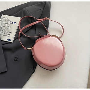 Détail du sac bandoulière en cuir verni rose avec finition brillante et fermoir doré
