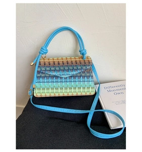 Detail of blue rainbow woven straw handbag with twisted handle and metal buckle