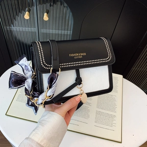 Detail of color-block square bag featuring black leather flap and silk scarf chain strap