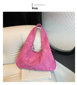 Close-up of pink underarm bag with quilted texture on cream sofa with books