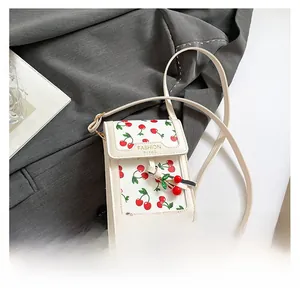 Detail of cherry print mini crossbody bag with leather strap and fashion charm