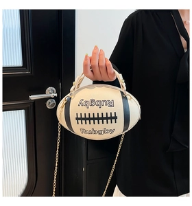 Detail of rugby-shaped crossbody bag in cream with black stripes and gold chain strap