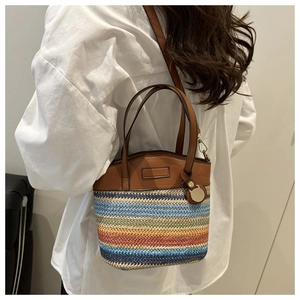 Shoulder shot of a multi-colored woven bucket bag with premium brown leather trim