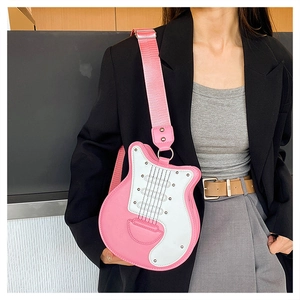 Gros plan d'un sac bandoulière rose en forme de guitare avec large sangle sur mannequin