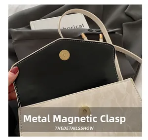 Close-up of the magnetic hardware snap button on a white marble pattern PU leather bag