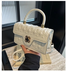 Detail of white quilted handbag with a gold clover lock and elegant top handle design