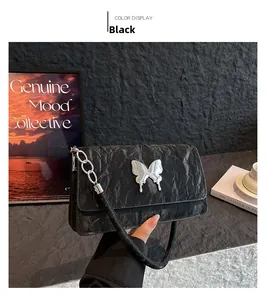 Detail of black quilted shoulder bag with silver butterfly clasp and chain strap texture